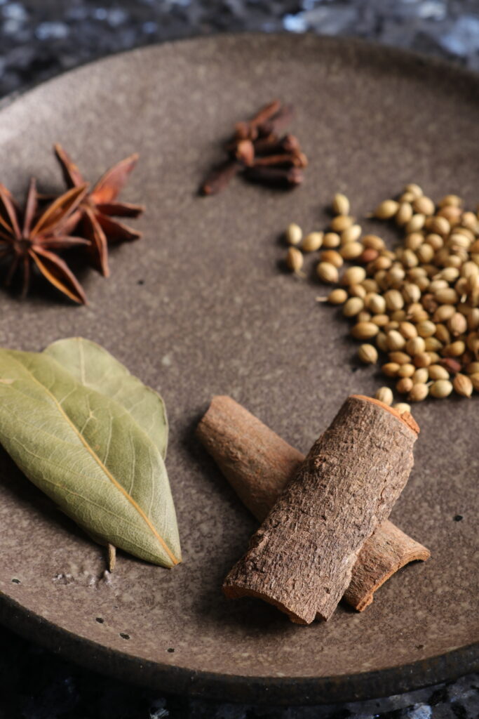 plate with bay leaves, cassia bark, coriander seeds, cloves and star anise