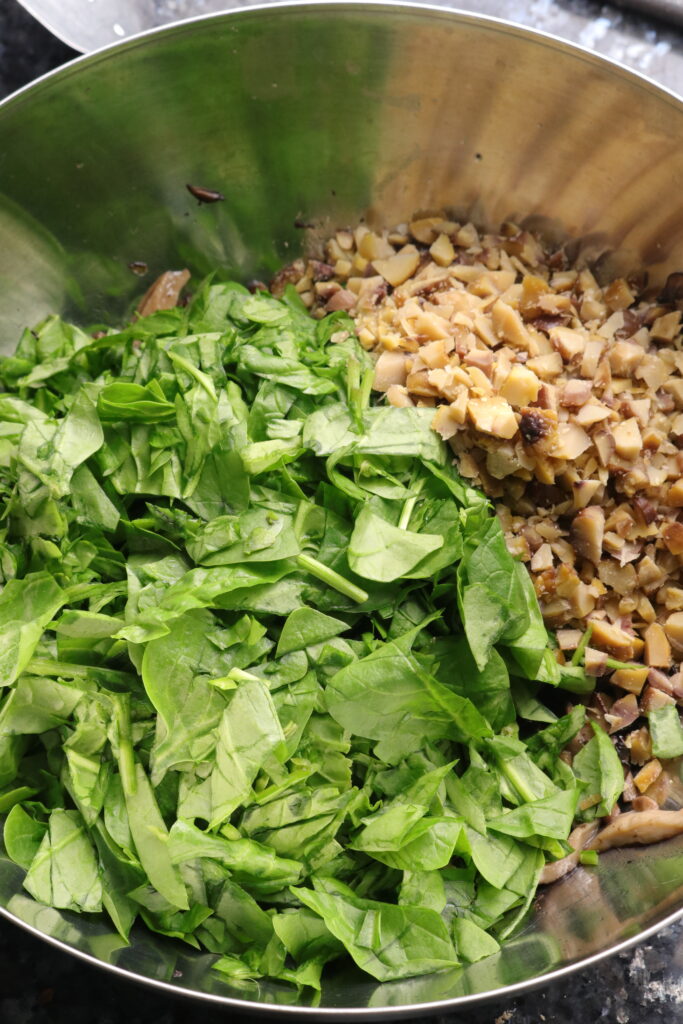 cooked mushrooms, spinach, and chestnuts in a mixing bowl