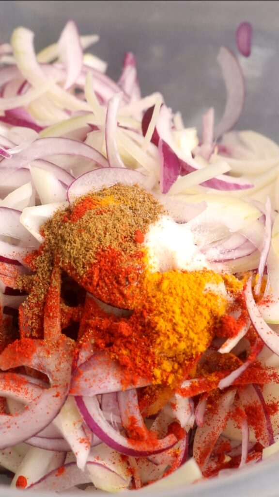 spices on top of onions in a mixing bowl