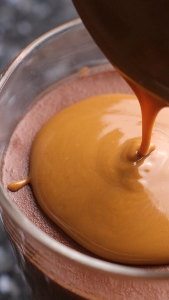 melted biscoff spread being poured on top of chocolate mousse