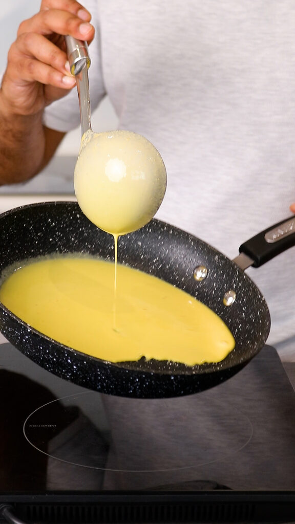 pouring saffron crepe batter into pan