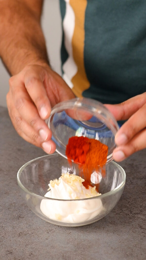 Vegan mayonnaise with grated garlic and chilli powder in a bowl  