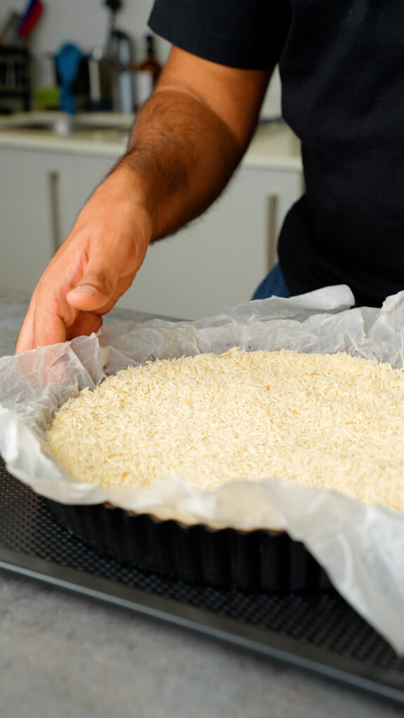 placing baking paper and dry rice over the chocolate shortcrust pastry for blind baking