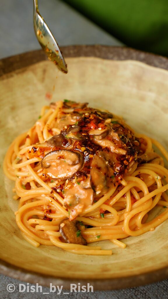 pouring chilli oil on top of chilli miso mushroom pasta