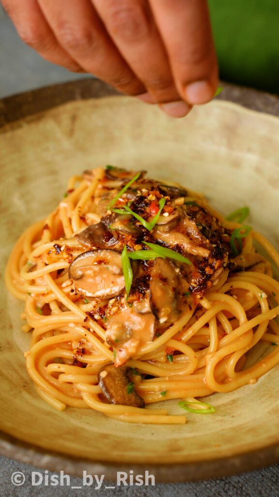 adding spring onions on top of chilli miso mushroom pasta