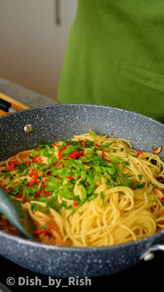 adding parsley, spring onions, and red chilli to the pasta