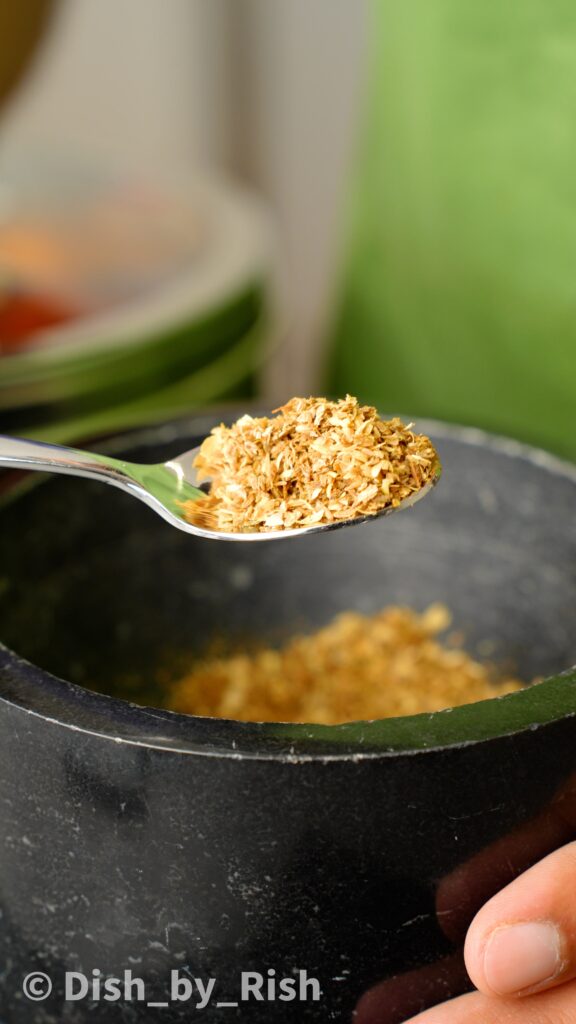 crushed coriander seeds, cumin seeds, and cloves in a pestle and mortar