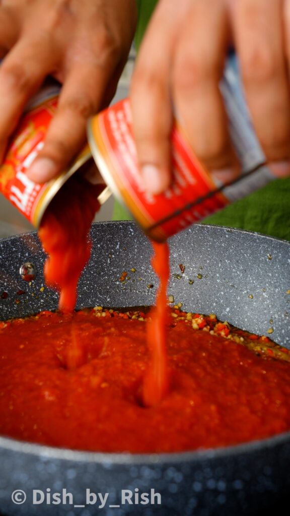 adding tinned tomatoes to the saucepan