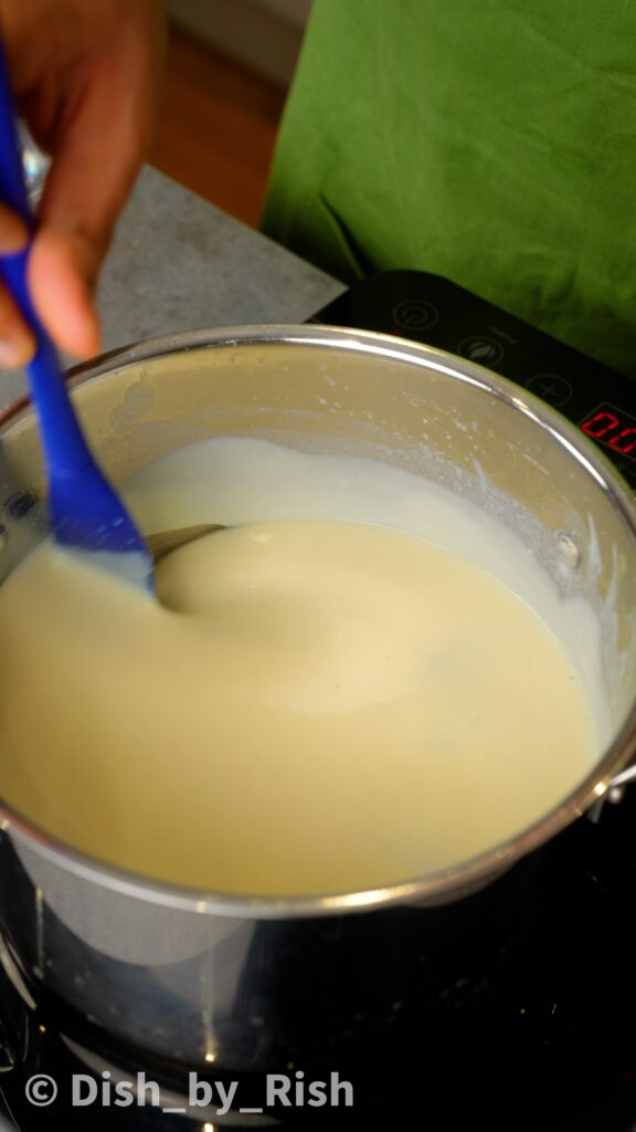 stirring béchamel sauce in a saucepan with a spatula