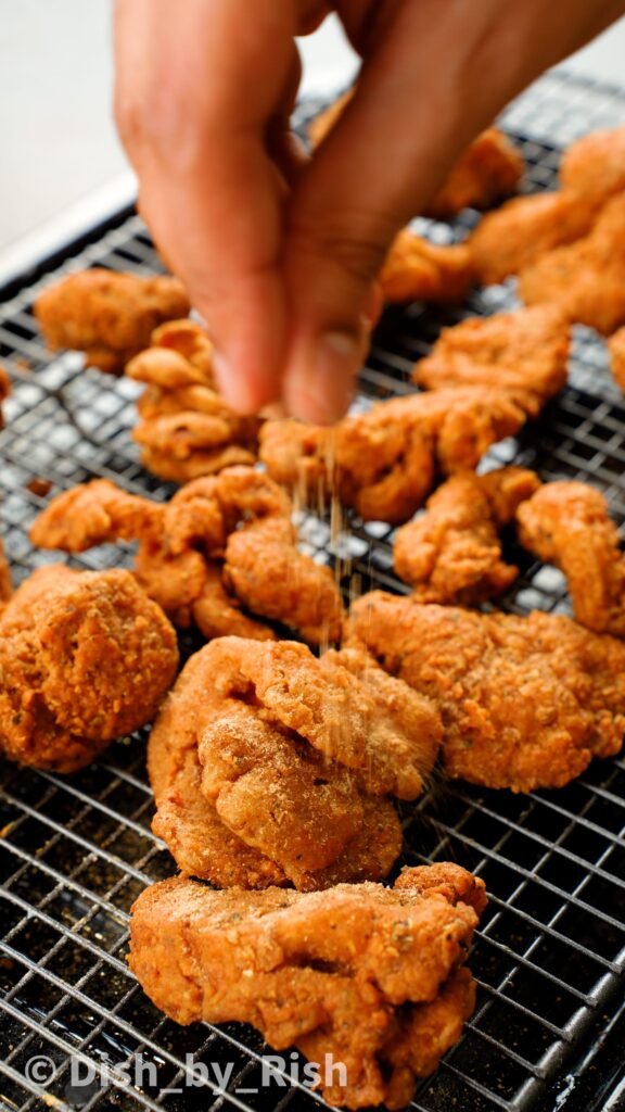 finishing masala fried oyster mushrooms with dried mango powder