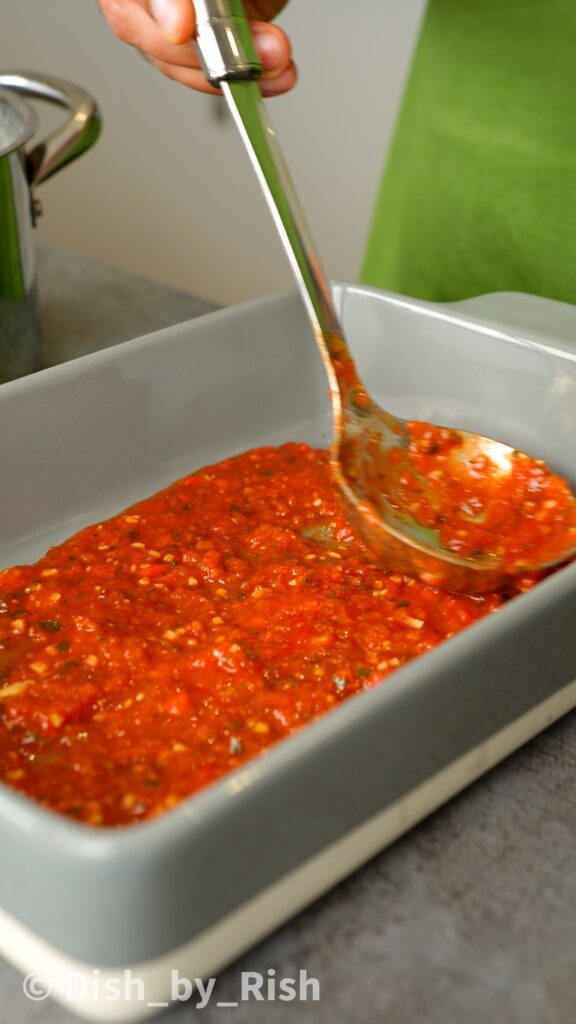 placing a layer of arrabbiata sauce at the base of a baking tray