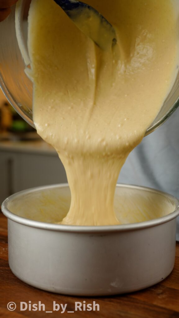 pouring cake mixture into 8 inch tin