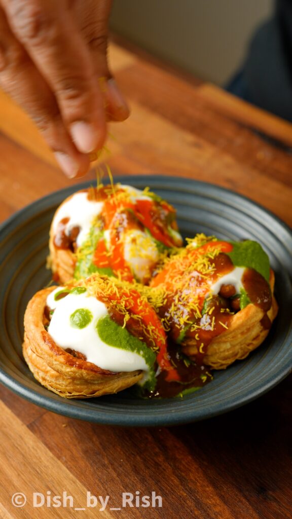 topping vol-au-vent chaat with yoghurt, chutneys, and sev