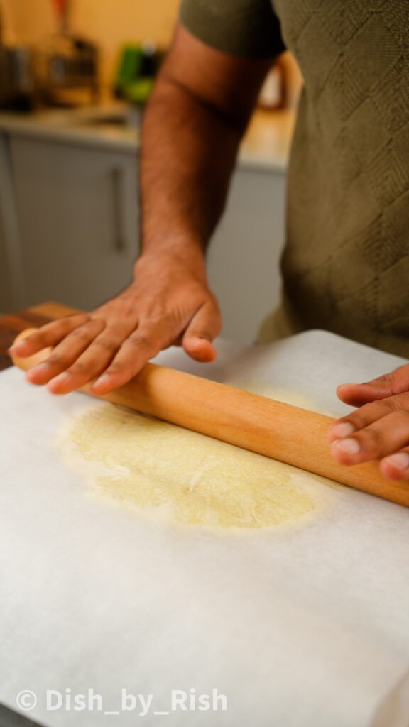 rolling out barfi between two sheets of baking paper