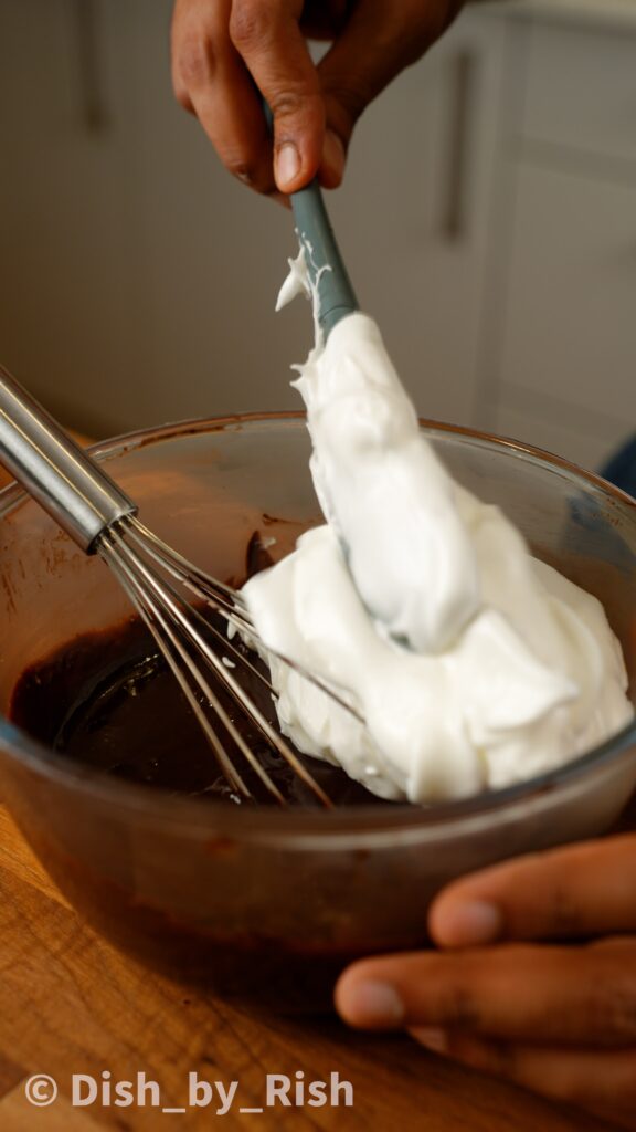 adding some of the whipped egg whites to the chocolate yolk mixture