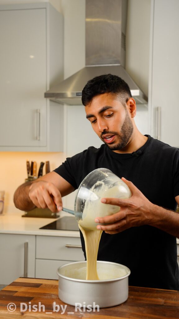 pouring eggless cake batter into greased and floured tin