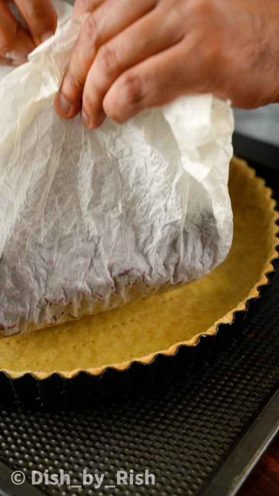 removing baking paper with beans from pastry