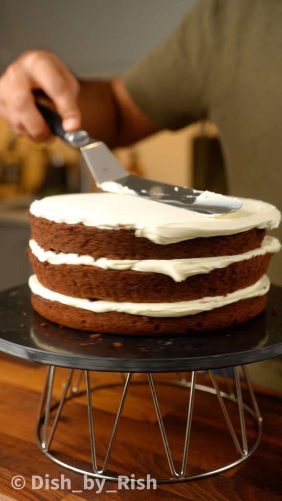 covering black forest chiffon cake with whipped cream