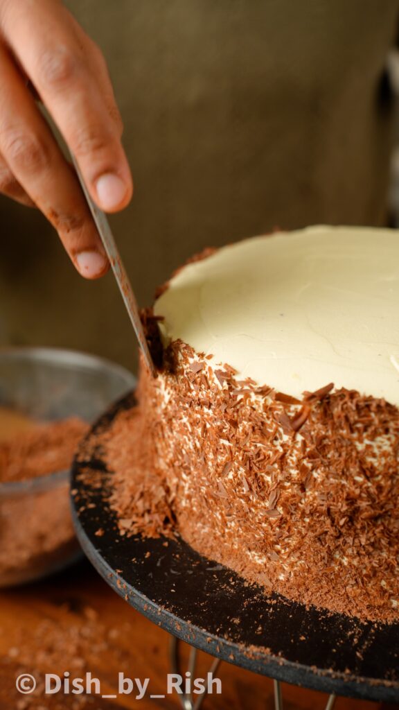 covering cake with chocolate shavings