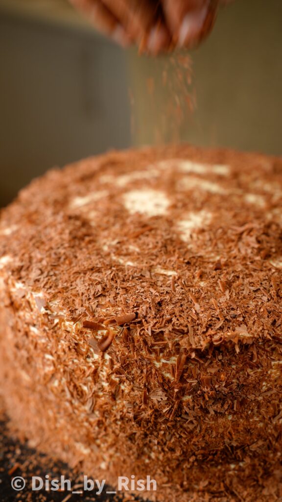 covering cake with chocolate shavings