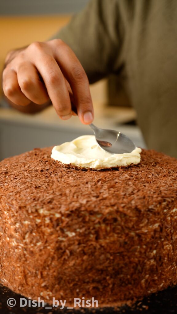 placing a dollop of whipped cream on top of the cake