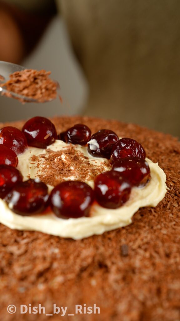 topping with glace cherries and more chocolate shavings