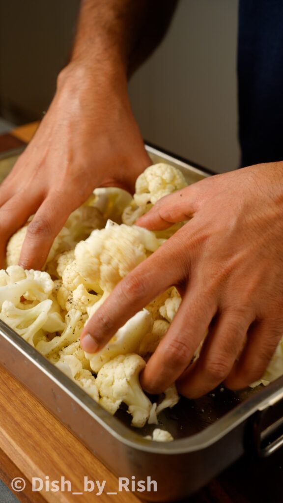 tossing cauliflower florets in roasting tray