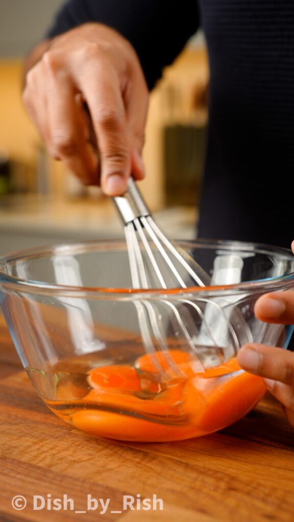 whisking egg yolks and oil in a mixing bowl