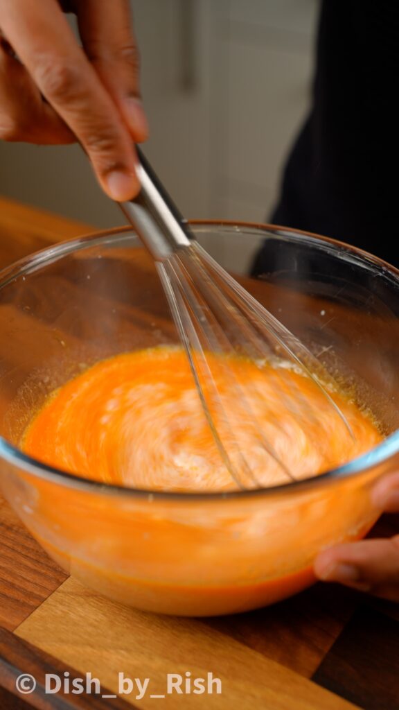 whisking egg yolks, oil, and milk in a mixing bowl