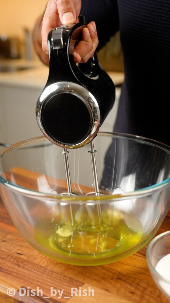 whisking egg whites in a large mixing bowl with electric whisk