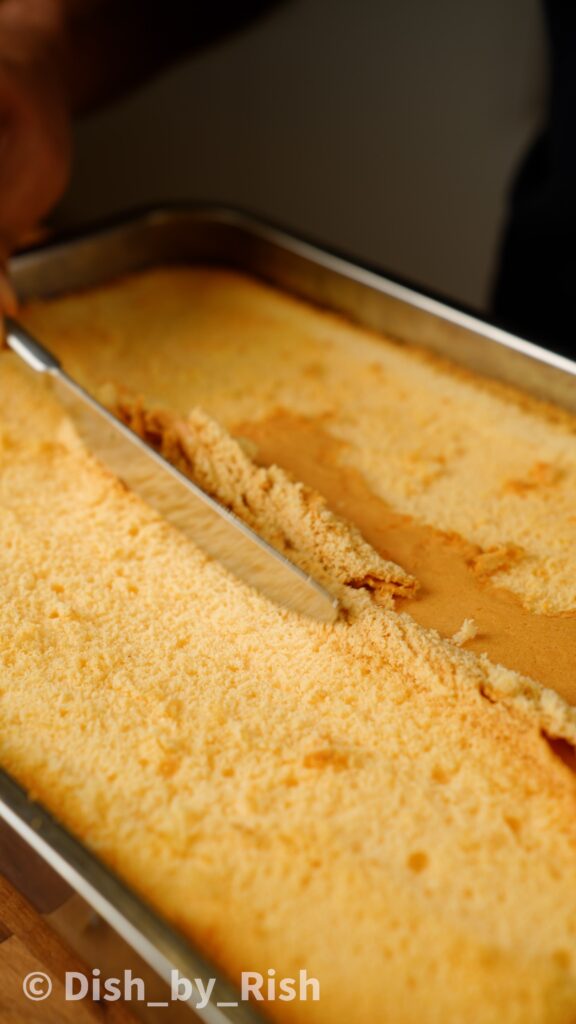 scraping off top layer of cake with a knife