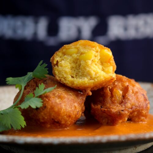 sweetcorn bhajia/sweetcorn bhaji/sweet corn fritters on a plate with chutney and coriander/cilantro