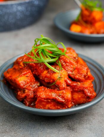 Szechuan Paneer in a bowl with another bowl of paneer behind