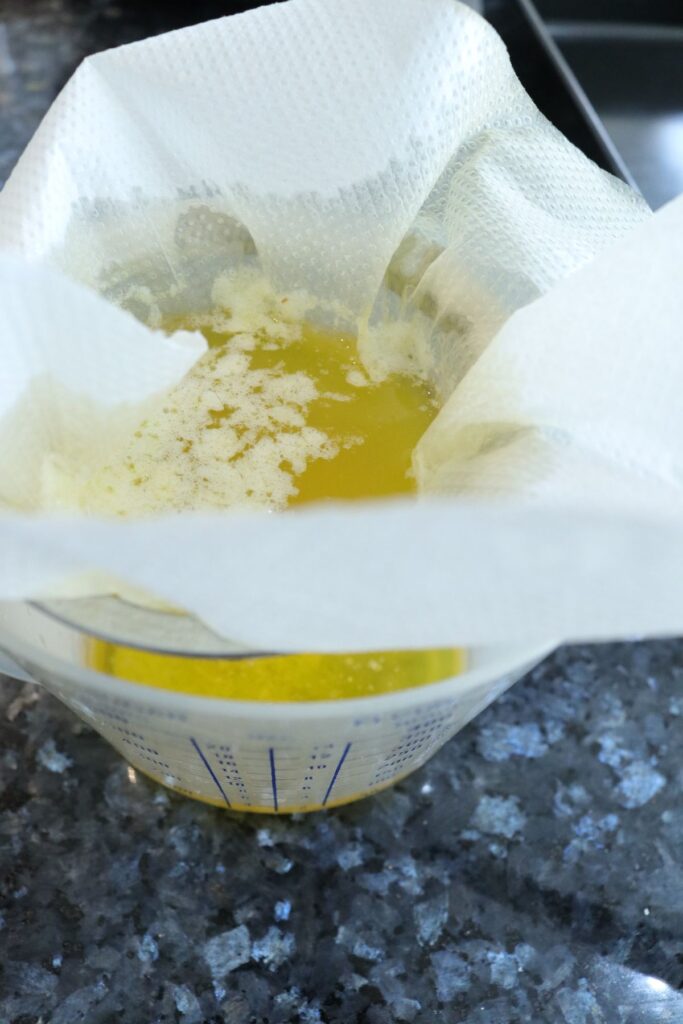 passing clarified butter through a sieve  lined with a paper towel into a bowl