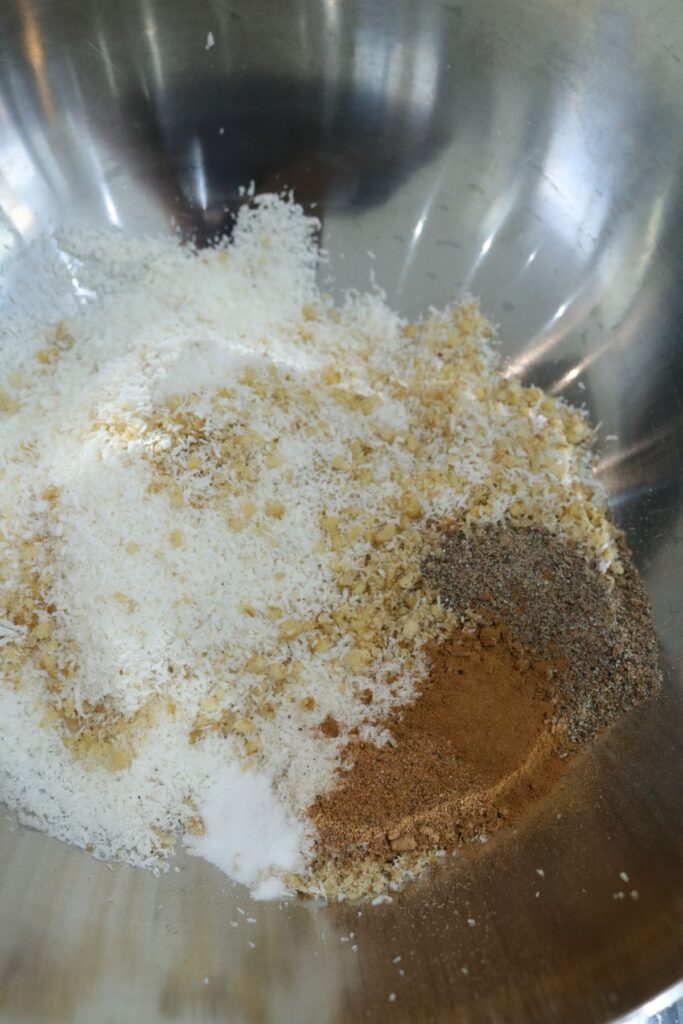 coconut, walnuts, cinnamon, and cardamom in a mixing bowl