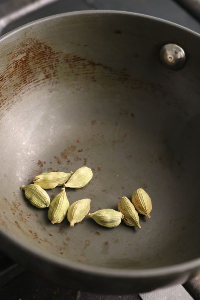 green cardamom toasting in a pan