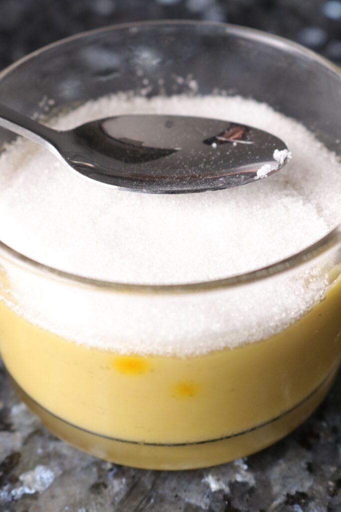 spoon with sugar on top of custard in a ramekin