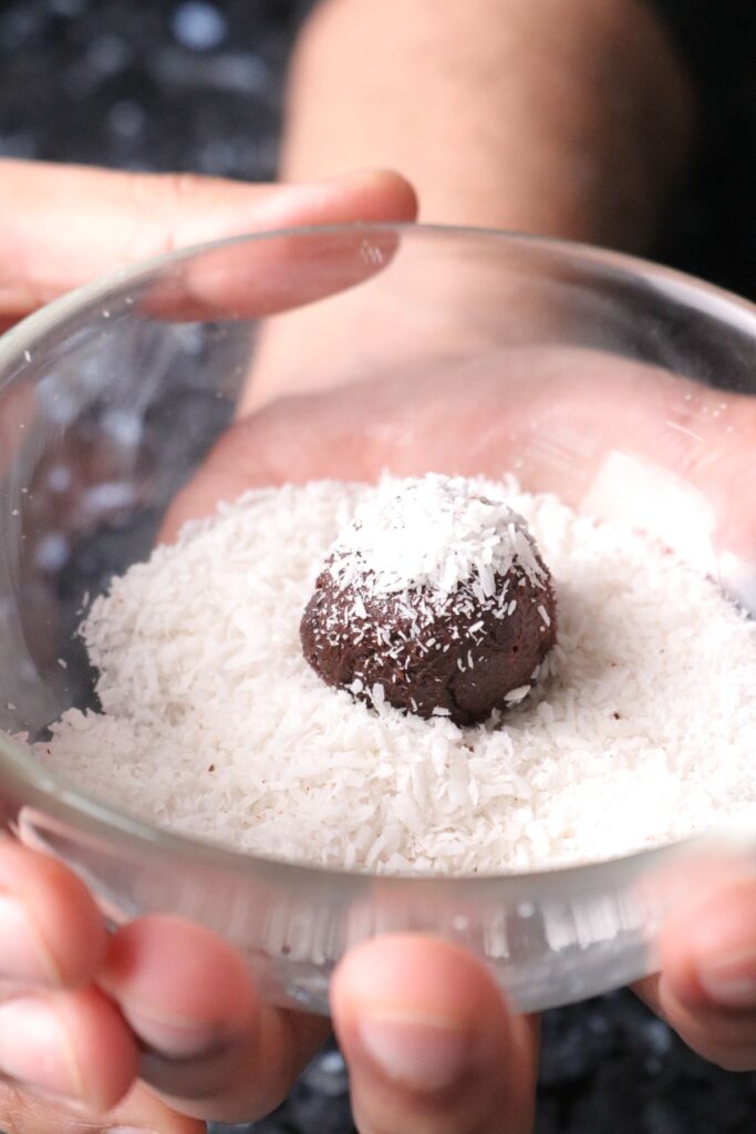 dark chocolate truffle being tossed in desiccated coconut