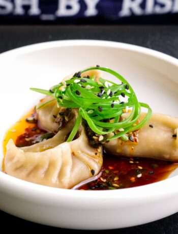 steamed veggie dumplings in a bowl with spring onions on top