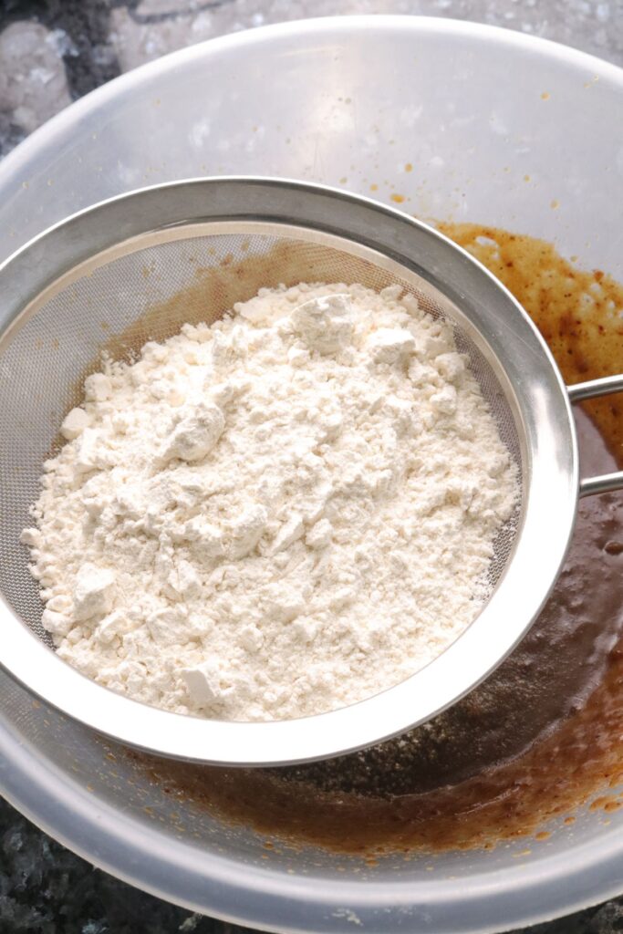 flour being sifted into wet mix