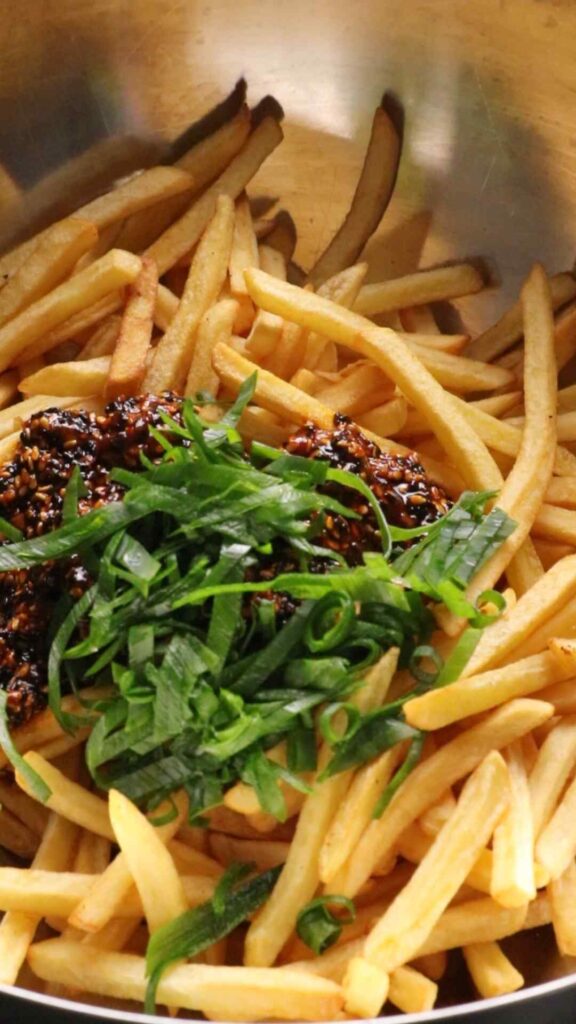 fries, sauce and spring onions in a bowl